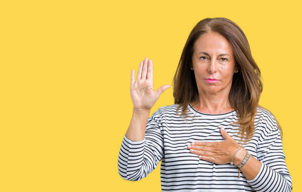 Beautiful middle age woman wearing stripes sweater over isolated background Swearing with hand on chest and open palm, making a loyalty promise oath