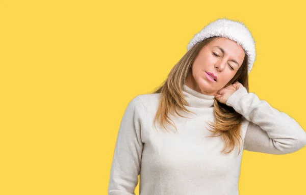 Beautiful middle age woman wearing winter sweater and hat over isolated background Suffering of neck ache injury, touching neck with hand, muscular pain