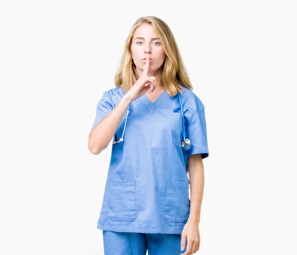 唇に指で静かにするように求めて孤立の背景に医療制服を着て美しい若い医者の女性 沈黙と秘密の概念 — ストック写真