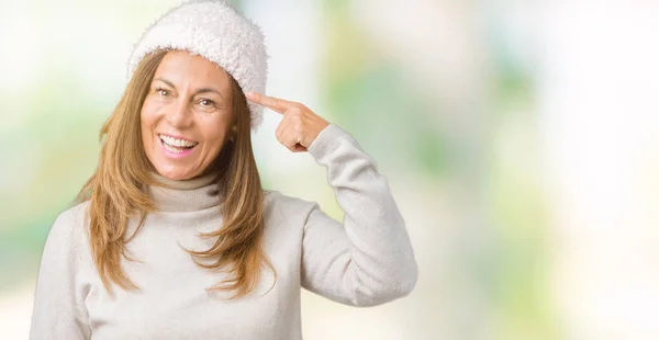 美丽的中年妇女穿着冬季毛衣和帽子在孤立的背景微笑指向头部用一个手指 伟大的想法或思想 良好的记忆力 — 图库照片