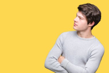 İkna ve kendine güvenen tarafına silahlarla seyir gülümseyen izole arka plan üzerinde kış kazak giyen genç yakışıklı adam geçti