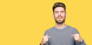 Yüzünde gülümseme ile kendinden emin görünüyorsun, kendini gururlu ve mutlu parmakları ile işaret çizgili süveter giyen genç yakışıklı adam.