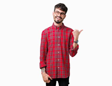 Seyir ve başparmak yanında yukarıyı mutlu yüz ile gülümseyen izole arka plan üzerinde gözlük takan genç yakışıklı adam.