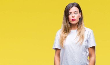 Genç güzel kadın rahat yüzünde ciddi bir ifade ile sarı arka plan üzerinde beyaz t-shirt. Basit ve doğal kameraya bakıyor.