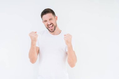Gülümseyen ve başarı için çığlık izole arka plan çok mutlu ve heyecanlı kaldırdı, silah ile kazanan jest yapıyor üzerinde rahat beyaz t-shirt giyen genç yakışıklı adam. Kutlama kavramı.