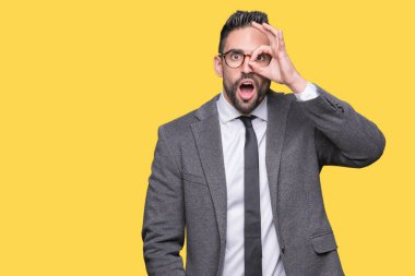 Genç yakışıklı iş adamı ok jest yapıyor izole arka plan üzerinde sürpriz yüz, göz parmaklarının arasından seyir ile şok. İmansız ifade.