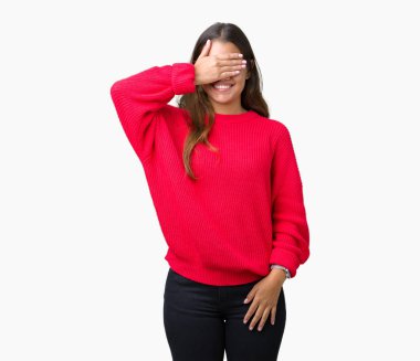 Gülümsüyor ve gözleri için sürpriz kapsayan yüz el ile gülüyor izole arka plan üzerinde kırmızı kış kazak giyen genç güzel esmer kadın. Kör kavramı.