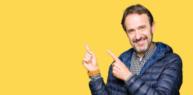 Orta yaş yakışıklı adam giyen kış ceket gülümseyen ve iki elleri ve parmakları ile tarafına işaret kamera bakıyor.