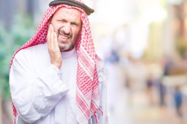 Diş ağrısı veya dişlerde dişlerle ilgili hastalık nedeniyle ağız acı ifadesi ile el ile dokunmak izole arka plan üzerinde keffiyeh giyen üst düzey Arap adam. Diş hekimi kavramı.