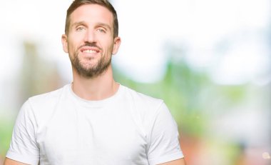 Yakışıklı adamın Casual beyaz t-shirt eller birlikte giydiğini ve parmakları rahat ve neşeli gülümseyen geçti. Başarı ve iyimser