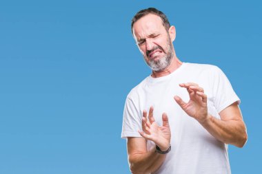 Orta yaş ağarmış komuta sizde izole arka plan üzerinde beyaz t-shirt giyen tiksinti ifadesi, memnun ve korkulu tiksinti yüz yapıyorsun çünkü nefret tepki. Elleriyle kaldırdı. Sinir bozucu kavramı.