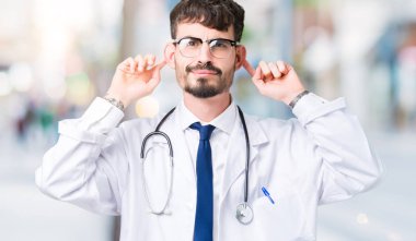 Genç izole arka plan gülen çekerek kulakları ile parmak, komik jest üzerine hastane ceket giyen adam doktor. Seçmelere sorun