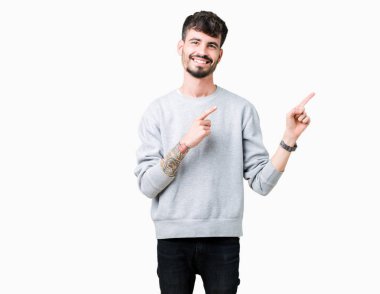 Gülümseyen ve iki elleri ve parmakları ile tarafına işaret kamera bakarak izole arka plan üzerinde sweatshirt giyen genç yakışıklı adam.