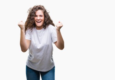 Güzel esmer kıvırcık saçlı Genç kız izole arka plan kutlama üzerinde rahat t-shirt giyen şaşırttı ve silah ile başarı için hayran kaldırdı ve gözleri açık. Kazanan kavramı.