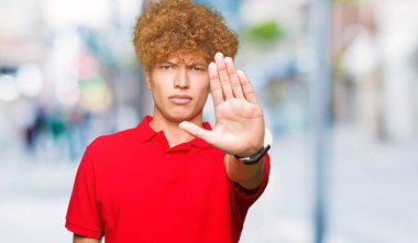 Genç yakışıklı adam kırmızı t-shirt giyen afro saçlı elin avuç ile şarkı stop yapıyor. Negatif ve ciddi bir jest yüz ifadesiyle uyarı.