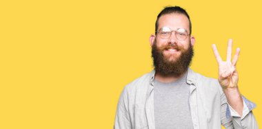 Kendinden emin ve mutlu gülümseyerek sırasında gösterilen ve parmakları ile işaret genç sarışın adam gözlük üçüncüsü.