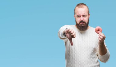 Genç beyaz hipster adam üzerinde tatlı çörek yeme arka plan kızgın yüzü, eksi işareti aşağı antipati başparmak ile gösterilen, ret kavramı ile izole