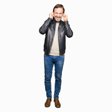 Orta yaş yakışıklı adam yüksek sesle müzik gürültü rahatsız ifade parmaklarıyla kulaklarıyla kapsayan siyah deri ceket giyiyor. Sağır kavramı.