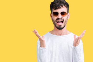 Yakışıklı delikanlı deli ve silah ile başarı için deli kutluyor izole arka plan üzerinde güneş gözlüğü takıyor kaldırdı ve heyecanlı çığlık gözler kapalı. Kazanan kavramı