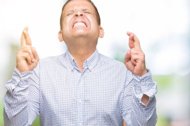 Orta yaş Arap iş adamı geçiş parmakları umut ve gözler gülümseyen izole arka plan üzerinde kapalı. Şans ve batıl kavramı.