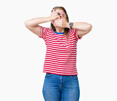 Orta yaş Olgun kadın izole arka plan kaplaması gözler ve ağız el ile üzerinden rahat t-shirt giyen şaşırttı ve şok. Duygu gizleme