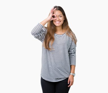 Gülümseyen, parmakları ile mutlu yüz üzerinden seyir göz el ile ok jest yapıyor izole arka plan üzerinde kazak giyen genç güzel esmer kadın çizgili.