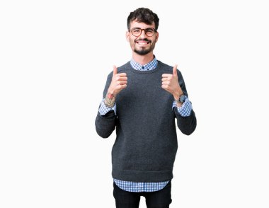 Genç yakışıklı zeki adam gözlüklü izole arka plan başarı işareti el ile pozitif jest yapıyor üzerinde başparmak gülümseyen ve mutlu. Neşeli bir ifadeyle, kazanan jest kameraya bakıyor.