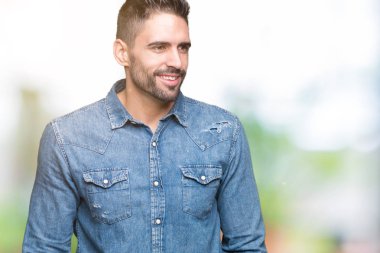 Yakışıklı delikanlı uzak tarafına yüzünde, doğal ifade gülümseme ile seyir izole arka plan üzerinde. Kendine güvenen gülüyor.