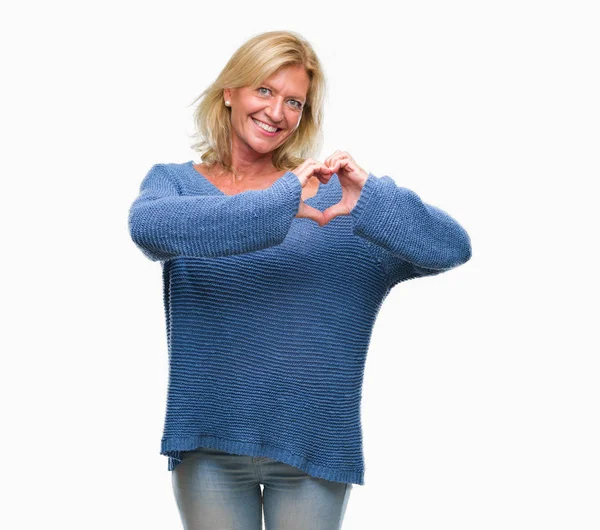 ハートマークと手で形を示す愛の笑みを浮かべて隔離された背景に冬のセーターを着て中年の金髪女性 ロマンチックな概念 — ストック写真