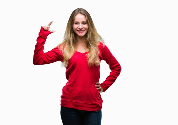 年轻美丽的金发碧眼的女人穿着红色毛衣在孤立的背景微笑 并自信地示意与手做大小标志与手指 而看和相机 测量概念 — 图库照片