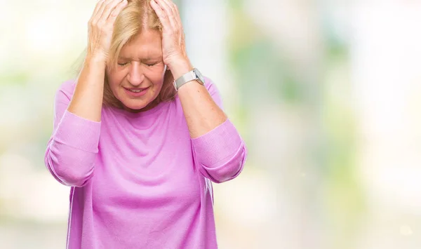 Middle age blonde woman over isolated background suffering from headache desperate and stressed because pain and migraine. Hands on head.