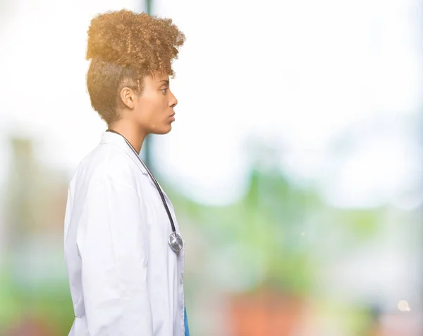 Young african american doctor woman over isolated background looking to side, relax profile pose with natural face with confident smile.