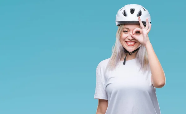 年轻的金发女子穿着自行车安全头盔在孤立的背景下做 手势用手微笑 眼睛看通过手指与愉快的面孔 — 图库照片