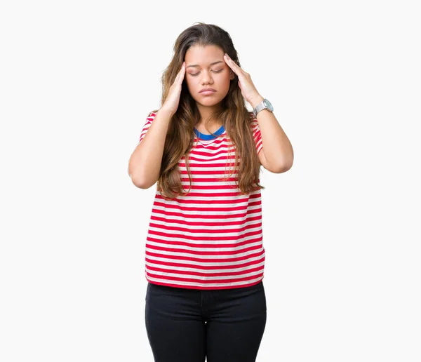 年轻美丽的黑发女人穿着条纹 T恤在孤立的背景与手在头上的痛苦在头因为压力 患有偏头痛 — 图库照片