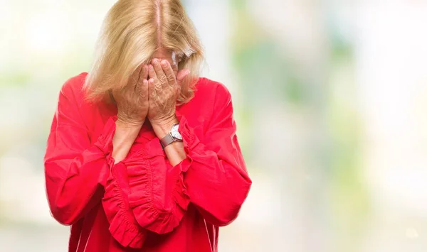 Middle age blonde woman over isolated background with sad expression covering face with hands while crying. Depression concept.