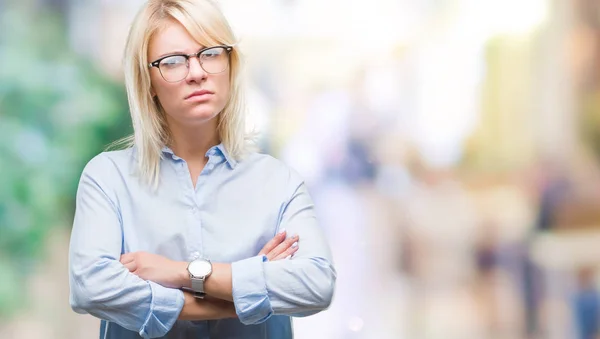 Young beautiful blonde business woman wearing glasses over isolated background skeptic and nervous, disapproving expression on face with crossed arms. Negative person.