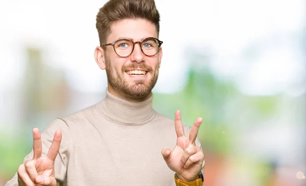 若いハンサムなビジネス人勝利のサインをやって指を表示するカメラを笑みを浮かべて 眼鏡をかけて — ストック写真