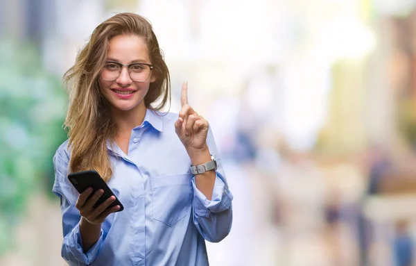 Young beautiful blonde business woman using smartphone over isolated background surprised with an idea or question pointing finger with happy face, number one