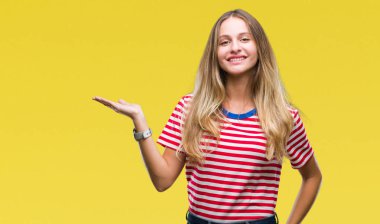 Neşeli sunulması ve kameraya bakarak avucunun ile işaret gülümseyen izole arka plan genç güzel sarışın kadın.