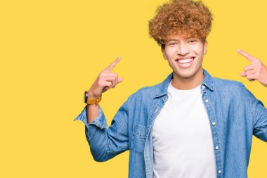 Afro saçlı kot giyen genç yakışıklı adam ceket hem el parmak, harika bir fikir ya da düşünce, iyi bellek ile baş gösteren gülen