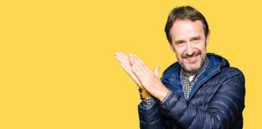 Orta yaş yakışıklı adam giyen kış ceket Clapping ve mutlu ve neşeli, gururlu gülümseyen eller birlikte alkış