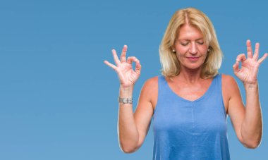 Orta yaş sarışın kadın izole arka plan üzerinde dinlenmek ve gülümseyen gözlerle parmak ile meditasyon jest yapıyor kapalı. Yoga kavramı.