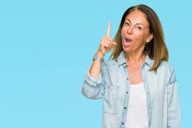 Orta yaş yetişkin kadın başarılı fikirle izole arka plan üzerinde işaret parmağı rahat kot gömlek giymiş. Çıktıktan ve mutlu. Bir numara.