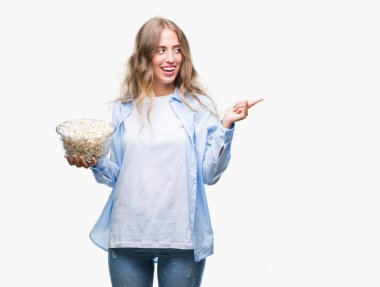 İzole arka tarafına el ve parmak ile işaret çok mutlu üzerinde patlamış mısır yemek güzel sarışın genç kadın