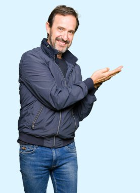 Bir ceket giyen orta yaş yakışıklı adam el ve reklam mutlu ve kendinden emin gülümseyen sunulması avuç, yanında işaret