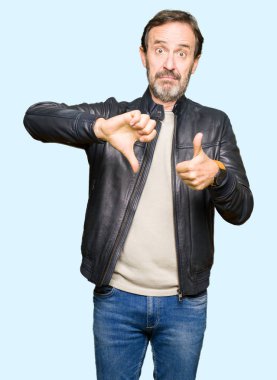 Orta yaş yakışıklı adam üzerinde siyah deri ceket yapıyor başparmak yukarı ve aşağı, anlaşmazlık ve anlaşma ifade. Deli çatışma