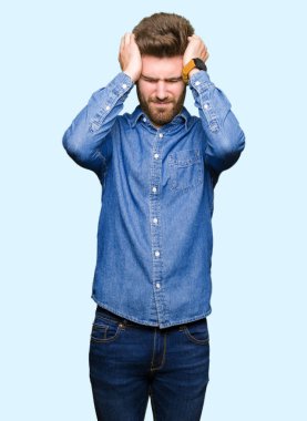 Genç yakışıklı sarışın adam rahat kot gömlek çünkü umutsuz ve stresli baş ağrısı acı acı ve Migren. Ellerini kafasına.