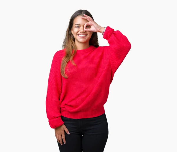 幸せそうな顔で指を通して見る目の手で のジェスチャーを行う分離の背景に若い美しいブルネットの女性身に着けている赤い冬セーター — ストック写真