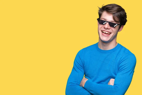 Young man wearing funny thug life glasses over isolated background happy face smiling with crossed arms looking at the camera. Positive person.