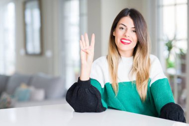 Evde kış kazak giyen genç güzel kadın gösterilen ve parmak dördüncü gülümseyen ise kendinden emin ve mutlu yukarı dönük.